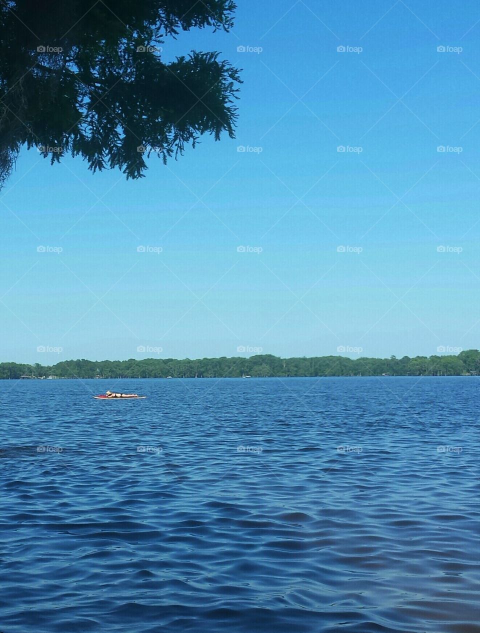 Woman laying on paddle board on lake