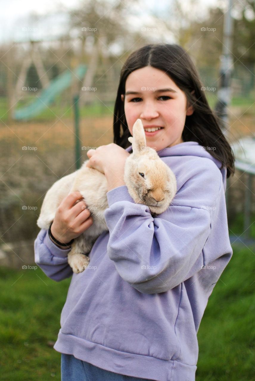 Teenager girl hugging her pet rabbit