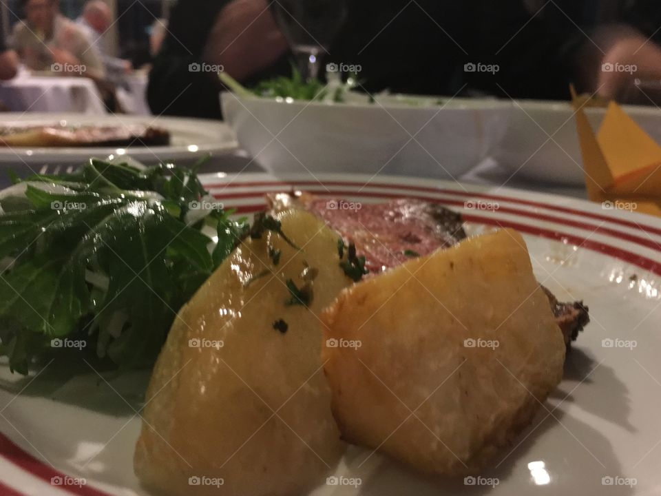 Closeup, fire pit roasted saltbush potatoes and kalrubi, barbecued beef on plate in gourmet restaurant