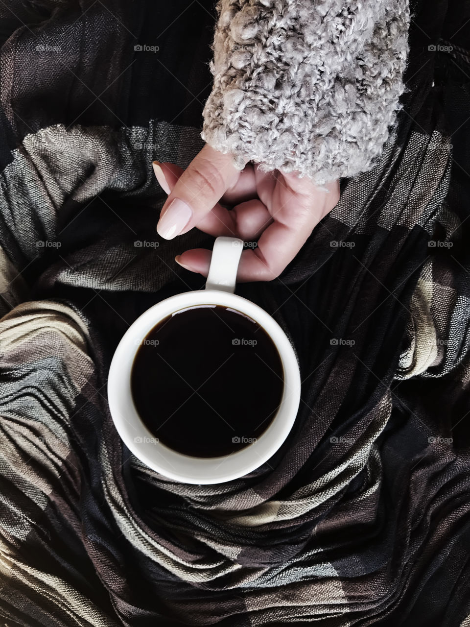 Young woman wearing cozy sweater and enjoying hot coffee in winter 
