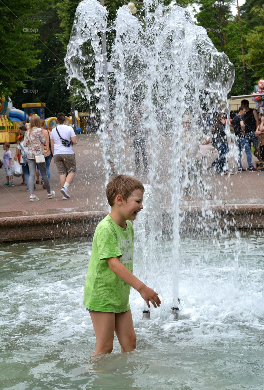 child in water fountain city summer time