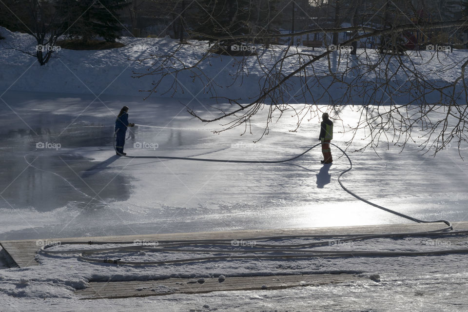 2 city workers out flooding the ponds for our door hockey. 
Great Canadian sport