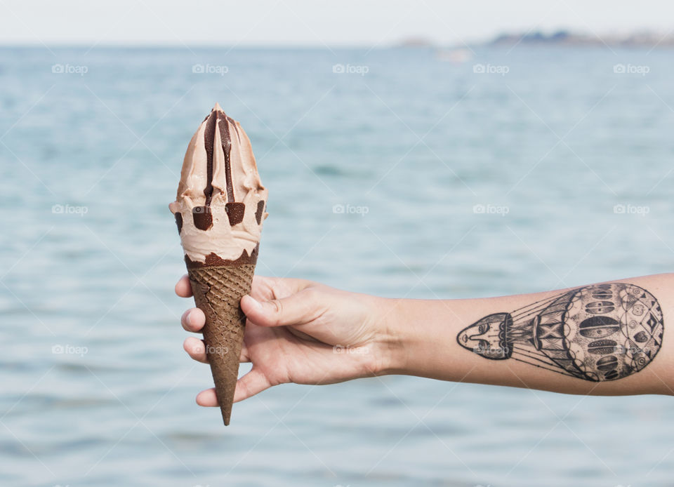 Hand holds an ice cream by the sea