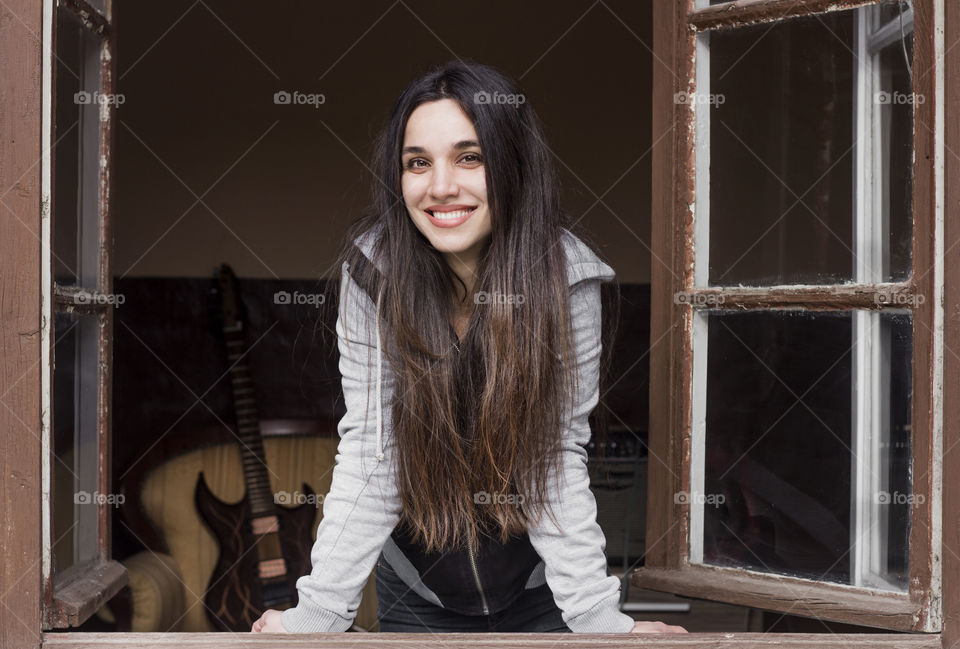 Beautiful woman smiling on the window of old house