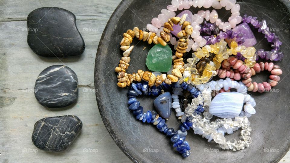 Gem stones in a black bowl with zen stones on a wooden background