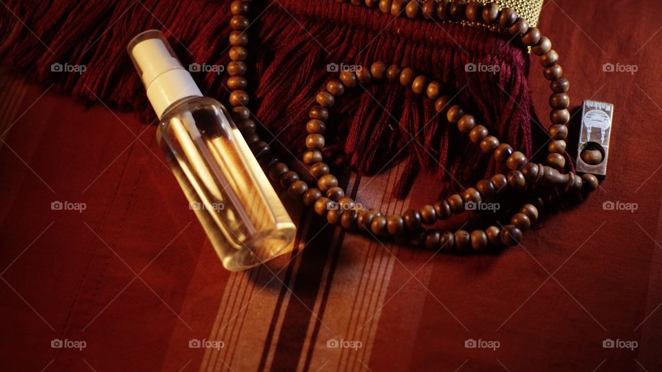 Hand sanitizer spray and wooden prayer beads on a prayer mat