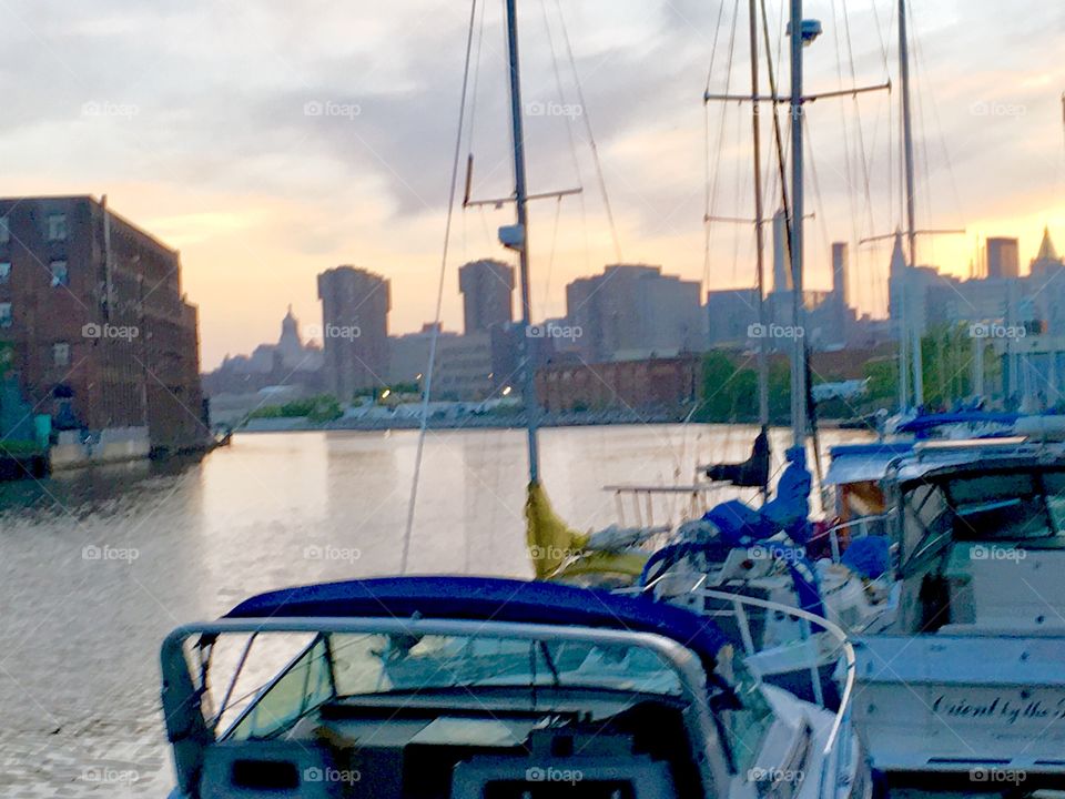 Boats in the water of Newtown Creek in Long Island City, Queens, New York as the twilight of dusk approaches. I took this picture in the Spring of 2019. You can see the Manhattan skyline in the distance. Hypnotic Productions