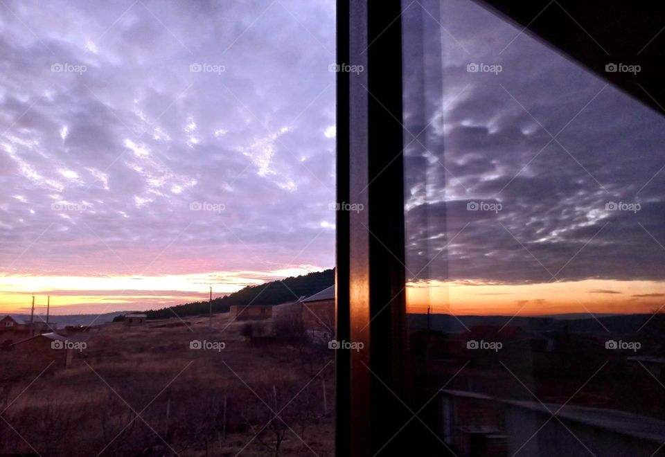 the sky during sunset and its reflection on the glass of the window.