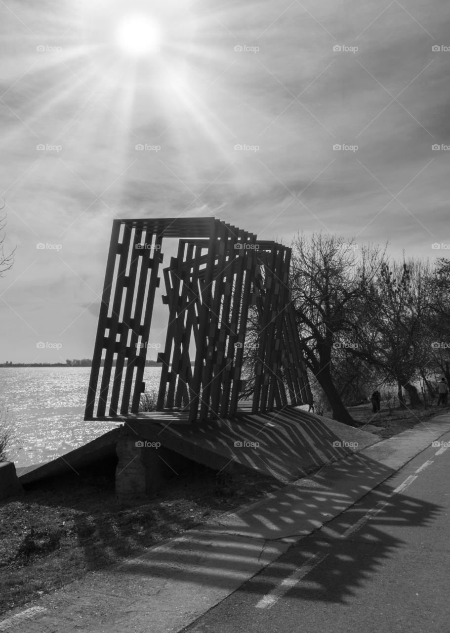Black and white photo with metal sculpture on sunny day.