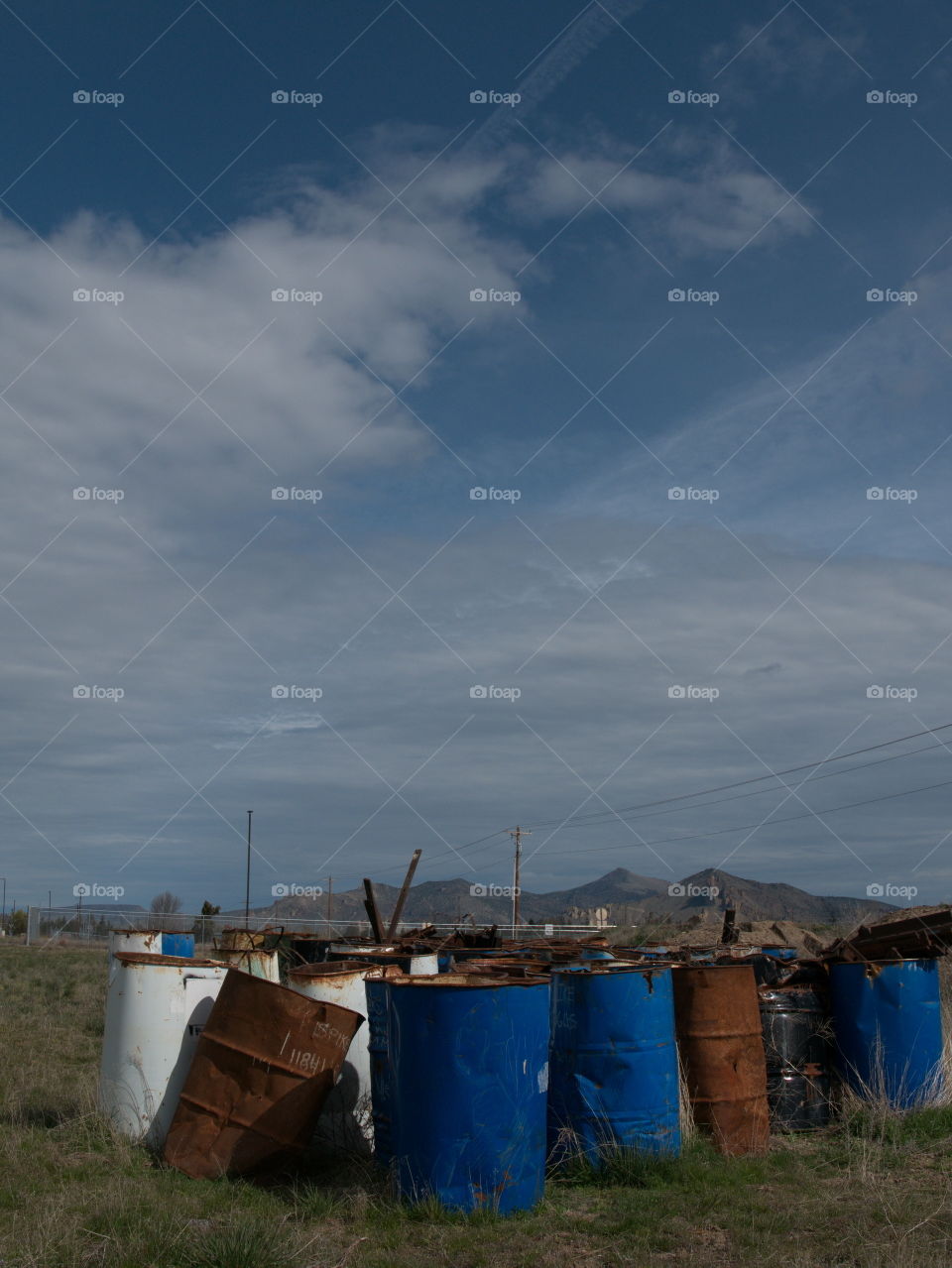 An abandoned bunch of oil barrels at an old train yard in rural Central Oregon on a sunny spring day. 