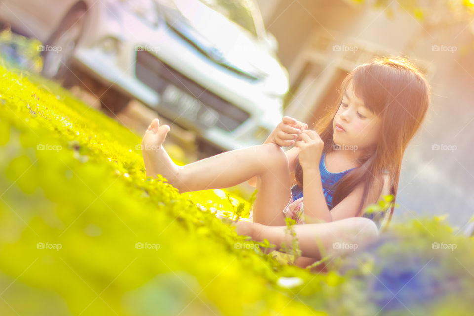 Asian girl sitting on grass in sunlight