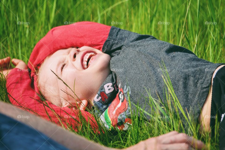 Happy laughing boy laying in the grass