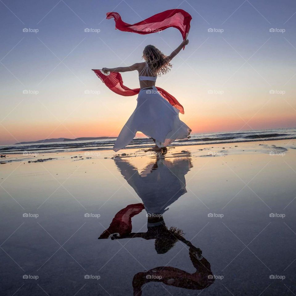 Woman dancing on beach at sunset