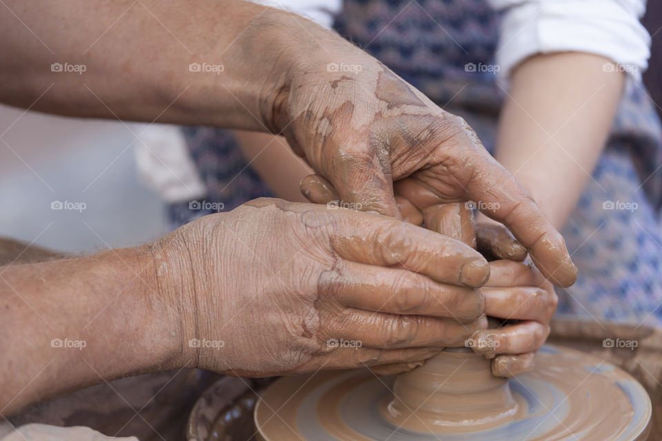 Close-up of two people's hand making pottery
