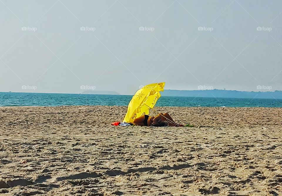 blissful afternoon sleep under the yellow umbrella in a summer day on the beach