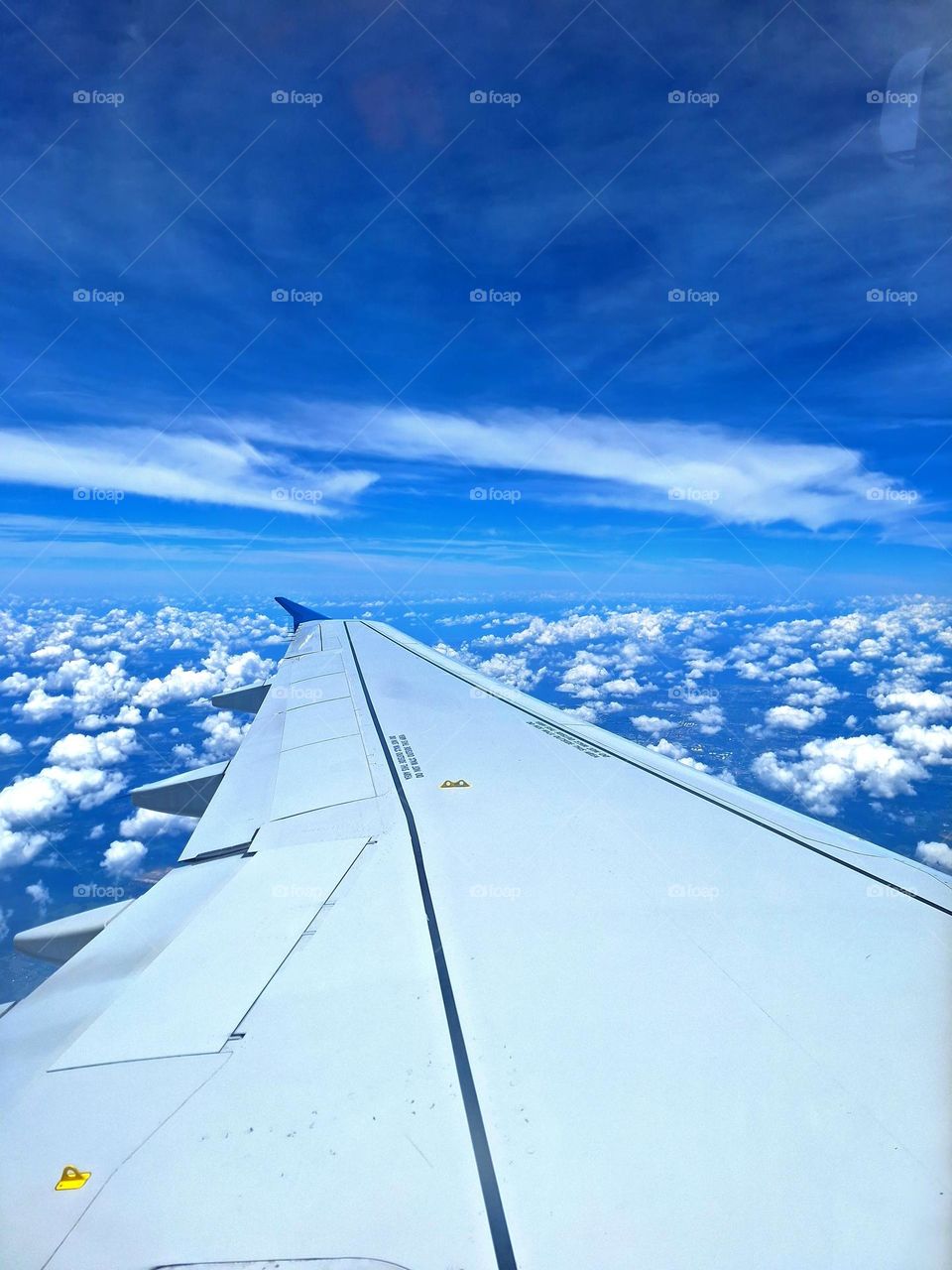 A view of the beautiful blue skies and puffy white clouds over the wing from the window seat of my vacation flight.