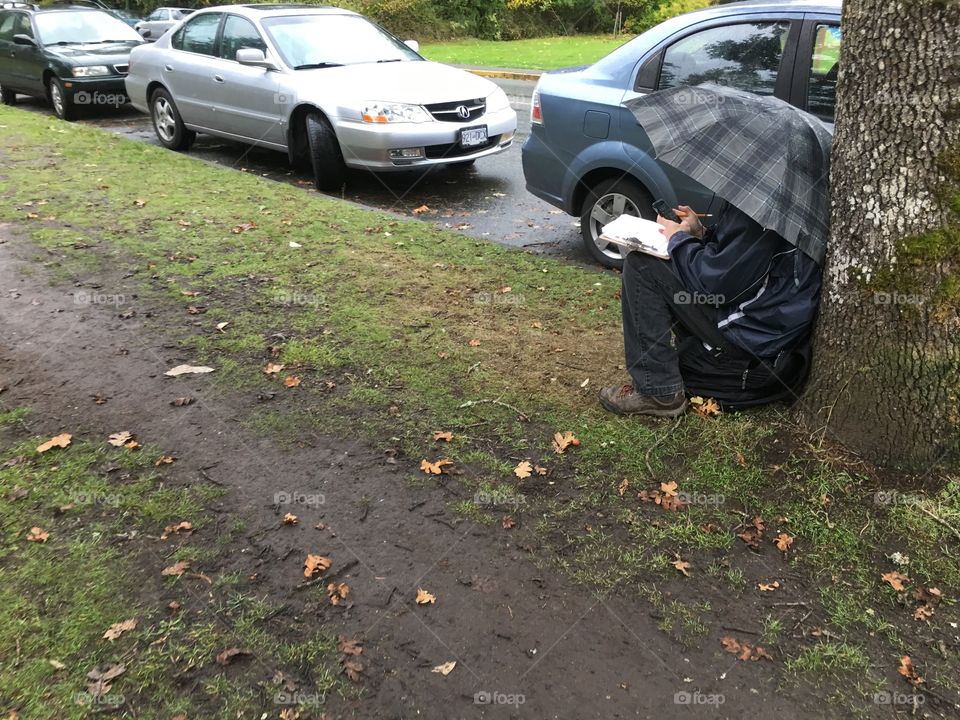 A person who reads under tree in a rainy day 