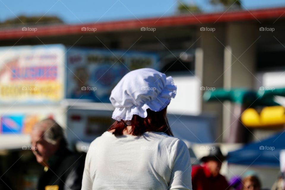 Woman wearing Cornish costume granny hat st outdoor festival back of head view 