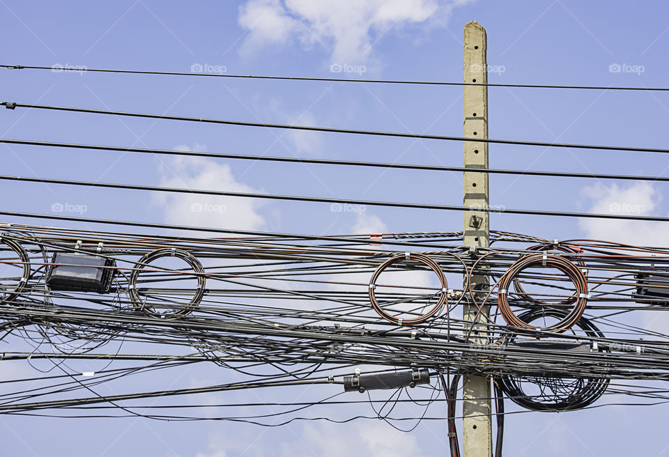 Electric wires and cables Hanging on a concrete pillar and the bright blue sky.