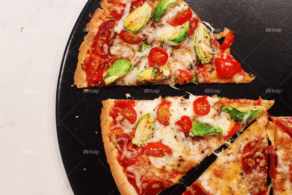 Homemade pizza on a black pizza stone.