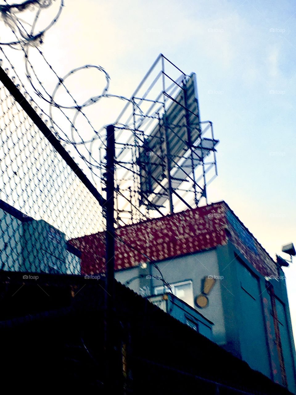Barbed wire fence and building underneath the Pulaski Bridge in Long Island City, Queens, New York photographed in the Spring of 2019.