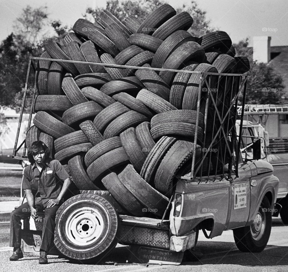 a driver of a truck carrying used tires waits for help to fix his own flat tire. flat tire. by arizphotog