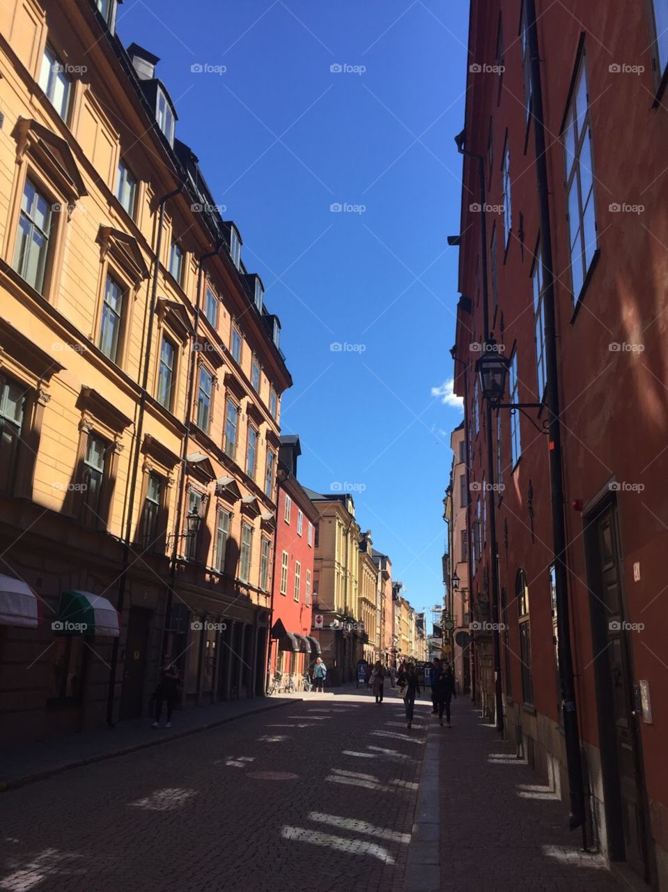 A narrow, Swedish street with tall, colorful buildings with many windows. 