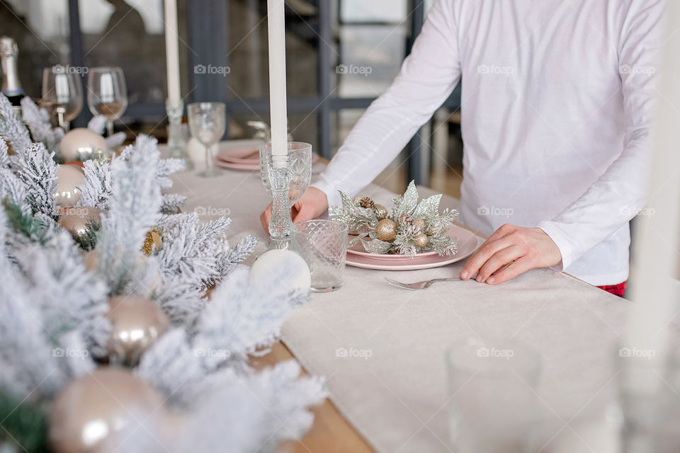 man sets a beautiful decorated winter table for a festive dinner.  Merry Christmas and Happy New Year.