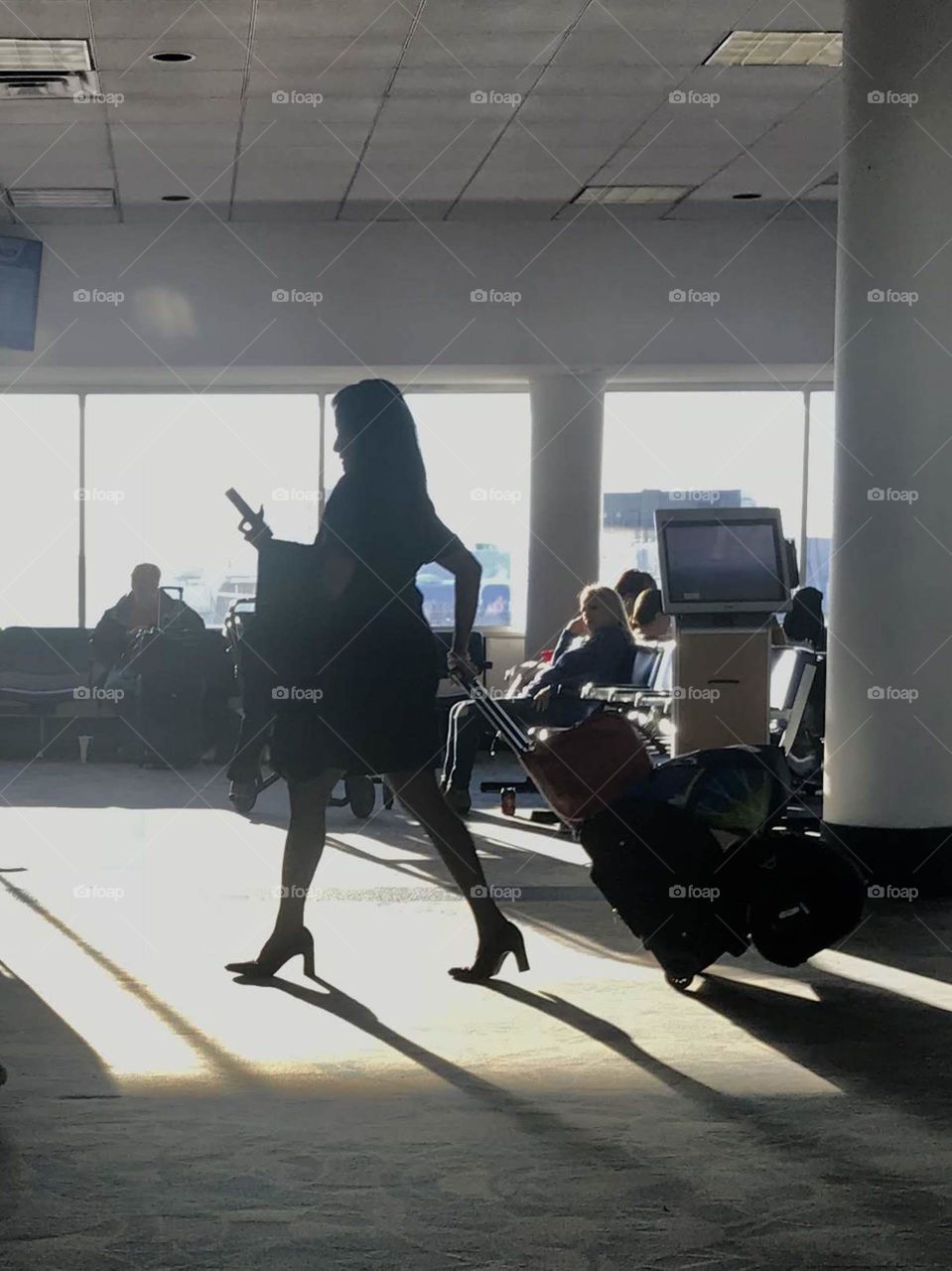 Woman walking in airport terminal while sun is setting casting shadow