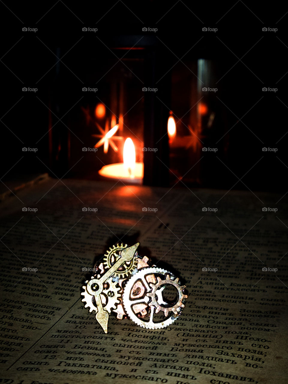 Clockwork from a clock on an old book in the light of a burning lantern