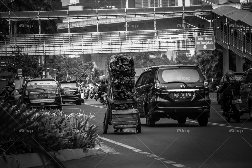 Jakarta, July 24,2019 - Old man with bare feet pulling out his old cart