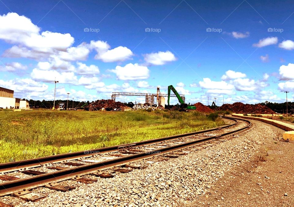 train tracks going through an industrial area on a beautiful day
