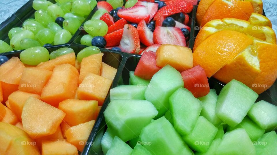 A tray of fresh fruit salad consisting of various fruit pieces with various vibrant colors.