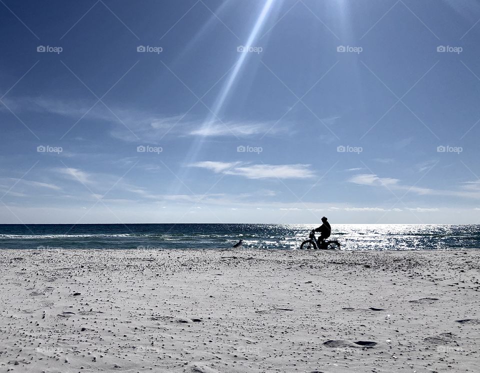 Silhouette of man riding bike on beach 