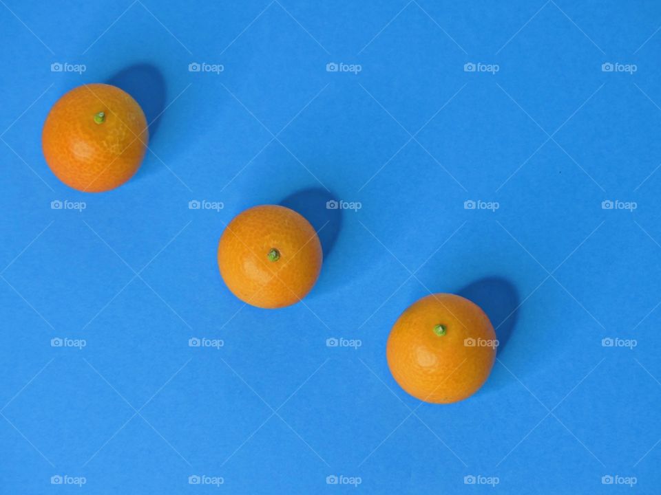 Blue x Orange - three oranges in a vertical position on a light blue background