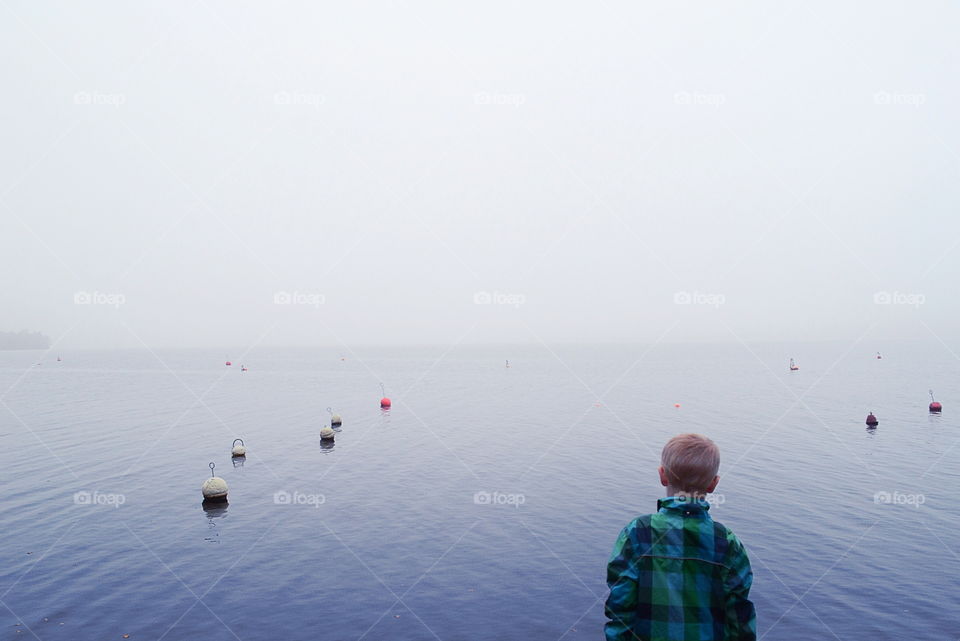 Boy at the lake a foggy morning