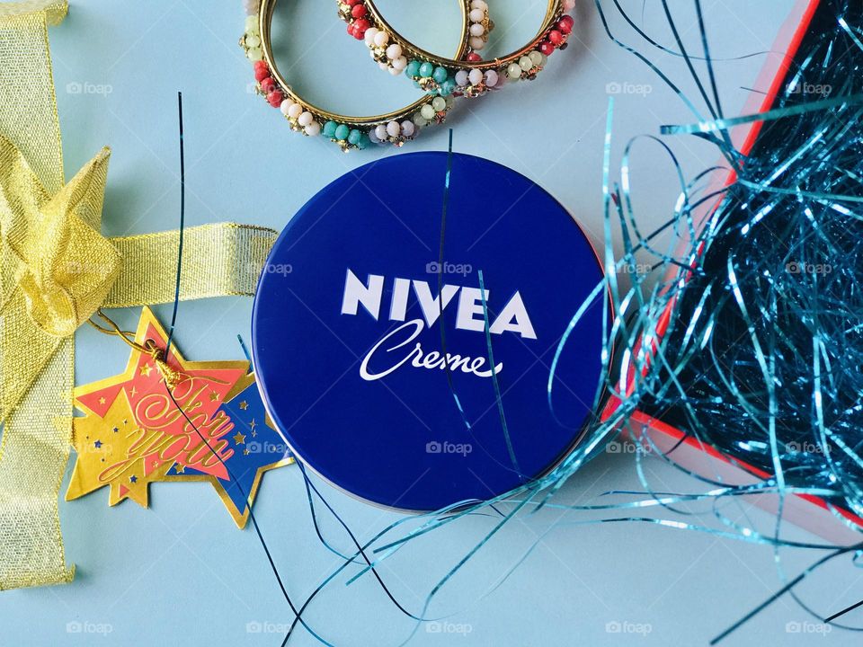 Nivea cream a gift box filled with blue glitter strips and beside that bangles and gift card labeled as for you.