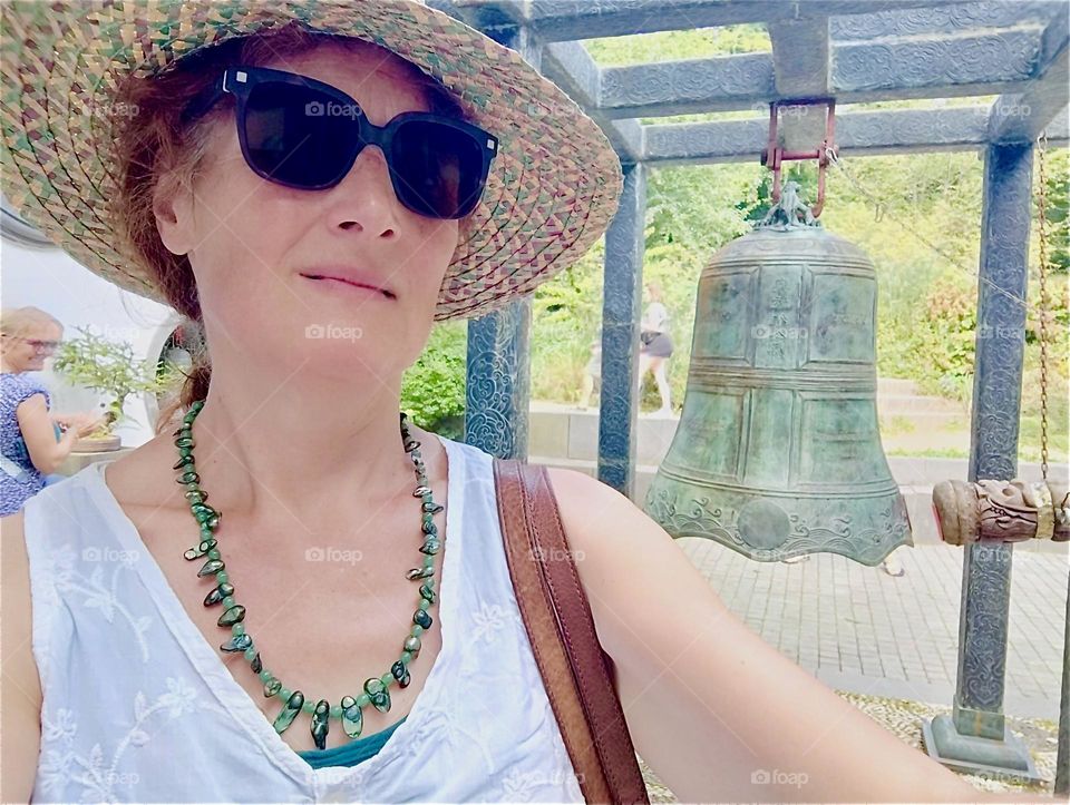 She enjoys her trip to “Himalaya Nepal Park” in “Wiesent”, “Bavaria”, Germany tremendously standing next to an oversized bell in one of the palatial temple buildings. 2024. Hypnotic Productions