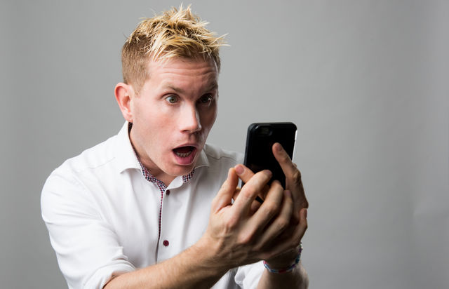 Surprise young man looking at mobile phone