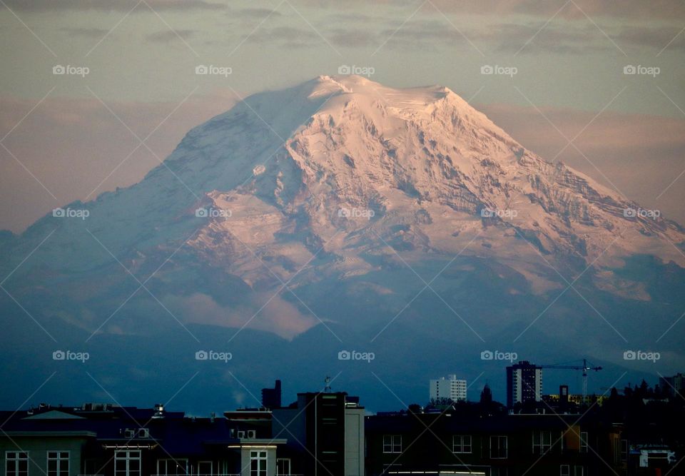 Snowy Mount Rainier stands majestic and overlooks the city of Tacoma in Washington State on a clear winter evening