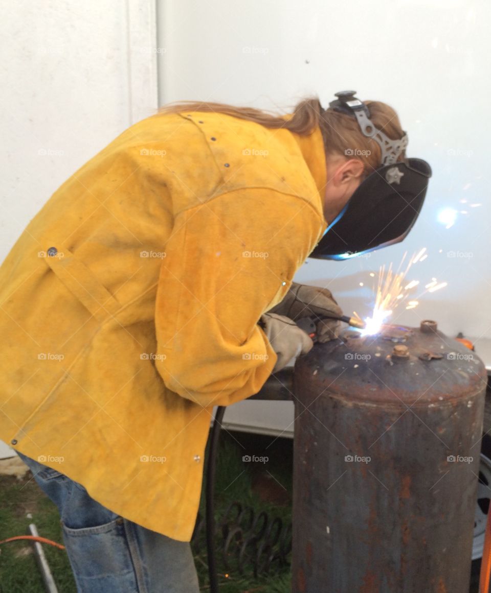 Weld. A man cutting torching and welding a piece of metal