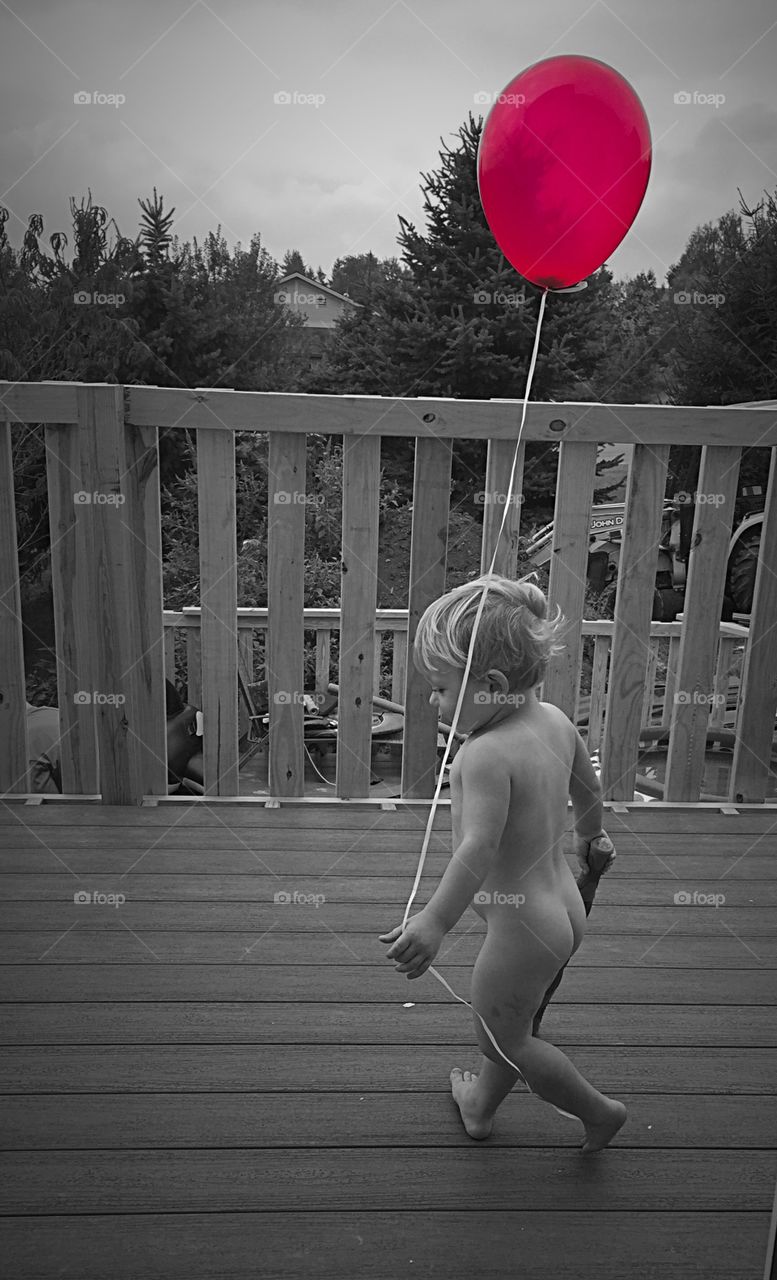 Boy with a Red Balloon. Little boy in his birthday suit, holding a red balloon. 
