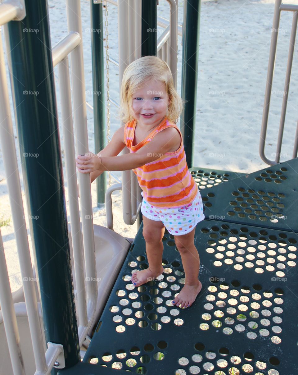 Cute blonde girl playing slide in park