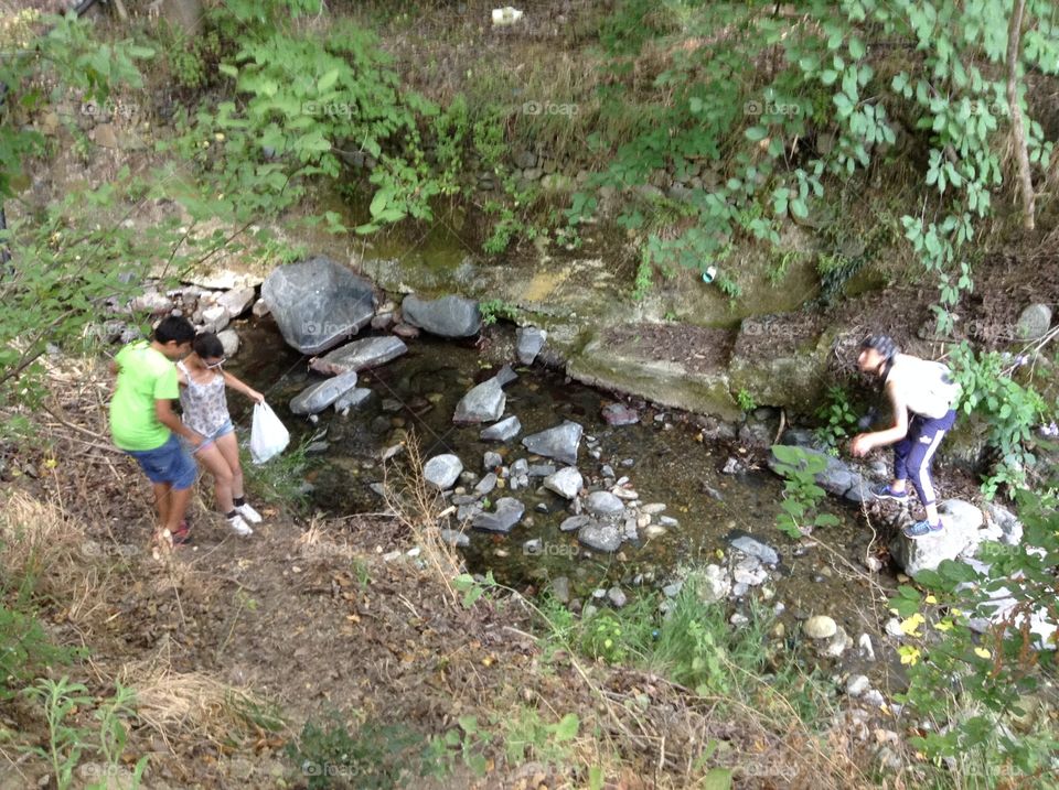 People hiking past a mountain stream.