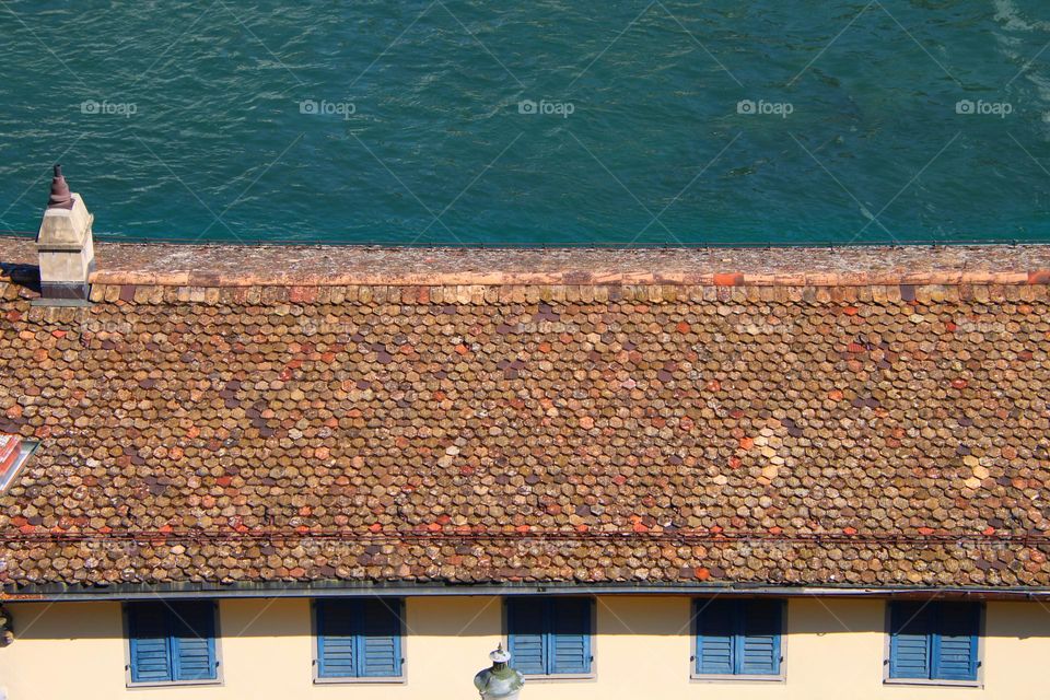 Colors, structure and pattern of a house with roof tiles by the green river from above