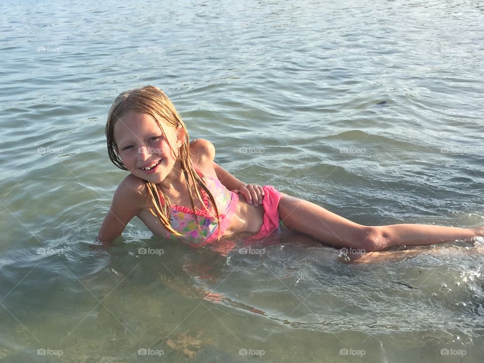 Little girl laying down posing in the ocean 