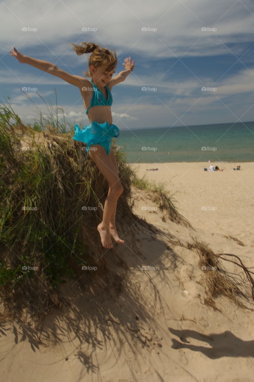 Young girl jumping off sand dunes