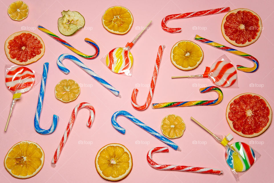 Lollipops and dried fruit layout on pink background