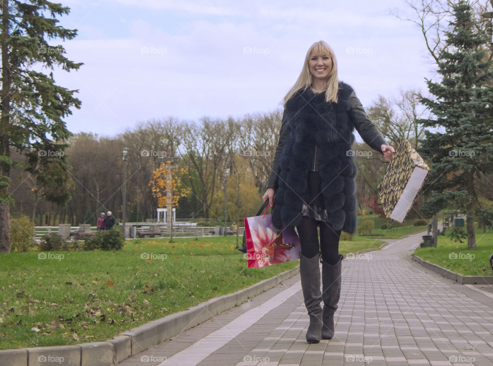 the girl is walking in the park with shopping