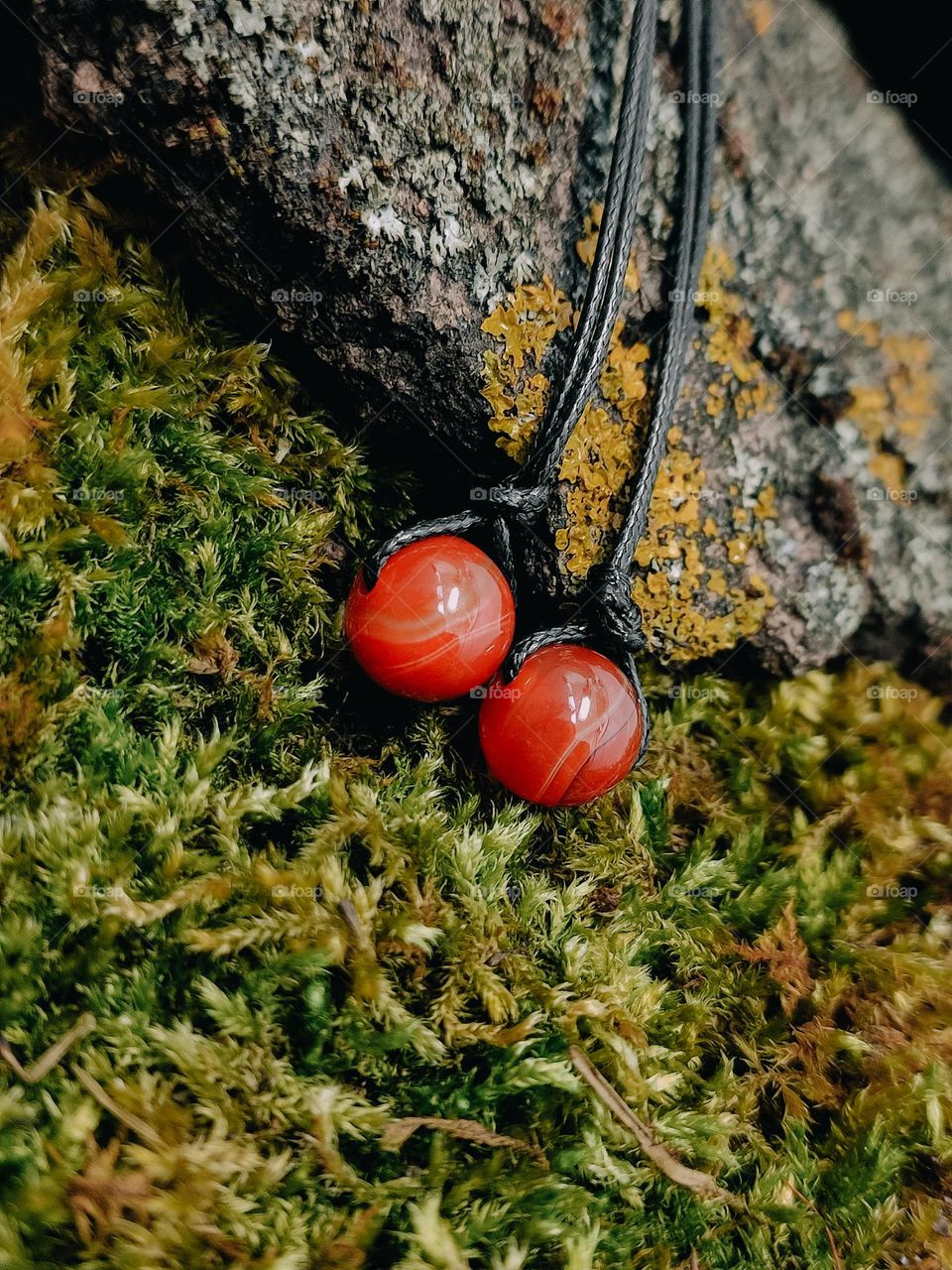 Cornelian stone chockers close up on the moss surface, gemstone beads on cord